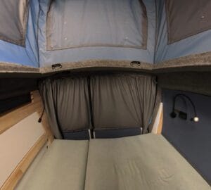 Caddy aménagé toit relevable par Karr Koncept : le lit arrière, rideaux occultants fermés