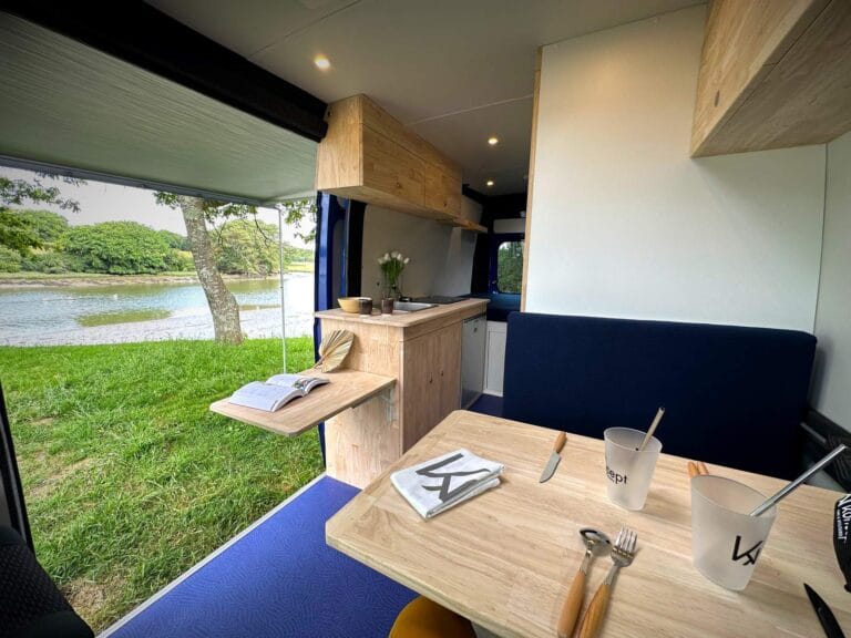 Grand van type camping-car par Karr Koncept : intérieur, table dressée, vue sur le lac