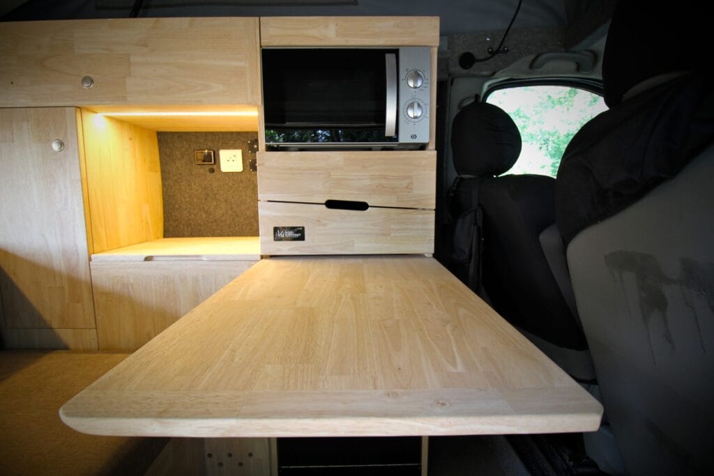 Van 4 couchages avec toit relevable par Karr Koncept : intérieur, table dépliée, cuisine et rangements