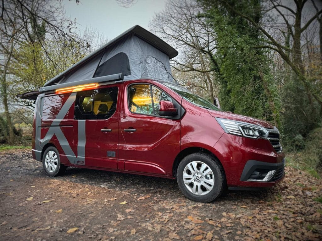 Van 5 couchages par Karr Koncept : le Renault Trafic rouge toit relevé ouvert, en forêt