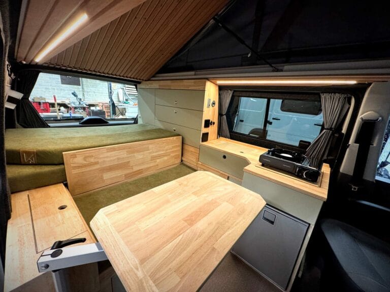 Van aménagé toit relevable par Karr Koncept : intérieur, table dépliée et banquette