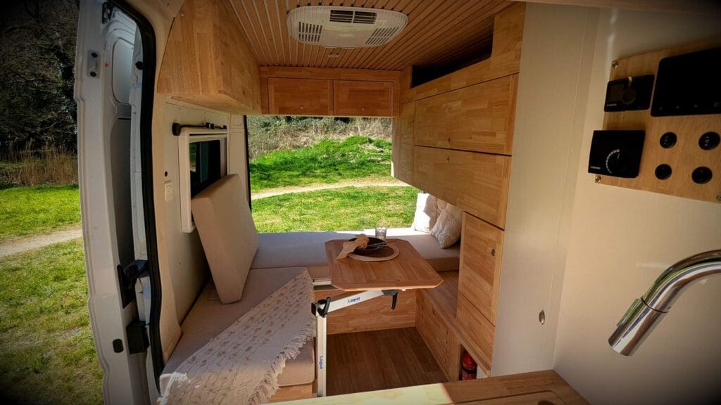Vivre dans un van par Karr Koncept : intérieur, table et vue sur la prairie