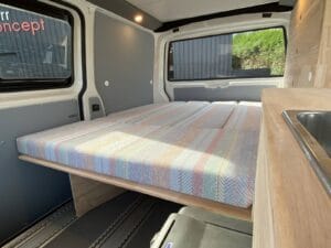 Alternative au Volkswagen California par Karr Koncept : lit déplié au-dessus de la glacière, à côté du plan avec évier