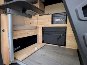 Mini van aménagé par Karr Koncept : rangements bas en hévéa massif avec abattant ouvert et pied de table rangé