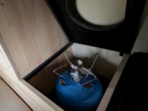 Mini van aménagé par Karr Koncept : coffre en hévéa massif ouvert sur la bouteille de gaz et le réchaud