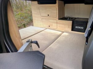 Mini van aménagé par Karr Koncept : lit déplié sur toute la largeur, cuisine en hévéa massif au fond