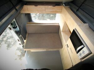 Van 4 couchages avec toit relevable par Karr Koncept : vue plongeante depuis le toit sur la banquette et le meuble cuisine