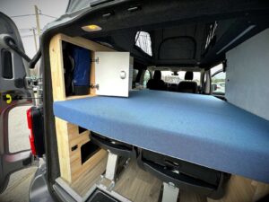 Van 4 personnes par Karr Koncept : hayon ouvert sur le couchage et un placard ouvert en hévéa massif