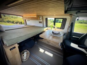 Van 4 places par Karr Koncept : vue d'ensemble avec couchage, table et plafond lambrissé en chêne massif