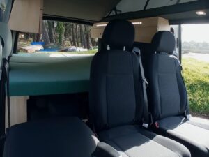 Van 7 places aménagé par Karr Koncept : sièges arrière devant le lit déplié, porte latérale ouverte sur la nature