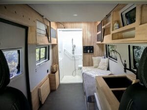 Van aménagé PMR par Karr Koncept : l'allée centrale vue de l'avant vers la douche, entre bloc cuisine et banquette