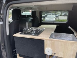 Van aménagé vanlife par Karr Koncept : le réchaud à couvercle et l'évier encastrés dans le plan de travail en hévéa