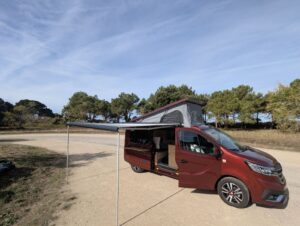 Van aménagé pour transporter un bateau par Karr Koncept : le Renault Trafic rouge, toit relevable ouvert et store déployé