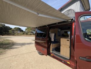 Van aménagé pour transporter un bateau par Karr Koncept : porte latérale ouverte sur le mobilier en hévéa massif et la tablette extérieure