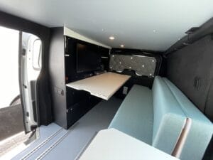 Van bureau mobile par Karr Koncept : le poste de travail avec tablette et écran face à la banquette, porte latérale ouverte