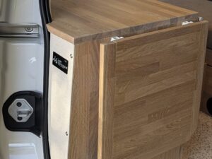 Van compact aménagé par Karr Koncept : la tablette rabattable fixée sur le flanc du meuble en chêne massif, près de la porte latérale