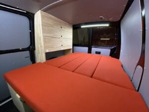 Van avec rangement pour fauteuil roulant par Karr Koncept : le lit déplié vu vers l'arrière, sous la réglette d'éclairage LED