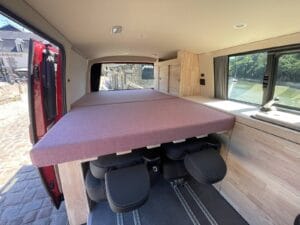 Van inspiration California par Karr Koncept : lit déplié au-dessus des sièges arrière, vu par la porte latérale ouverte