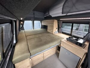 Van modulable tout démontable par Karr Koncept : couchage déplié sous le toit relevable, à côté de la cuisine et du réchaud