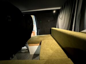 Van pro et loisirs par Karr Koncept : la banquette en L aux coussins verts et les rideaux occultants gris