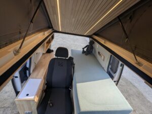 Van salon de massage par Karr Koncept : toit relevable ouvert vu de l'intérieur, siège et table de massage
