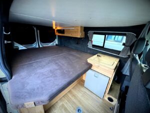 Van sans ondes électromagnétiques par Karr Koncept : la banquette dépliée en grand lit sur le plancher façon parquet